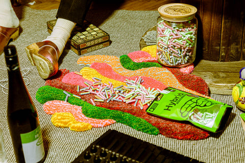 Grüne Hybrid Bag mit 250 bunten Aktivkohlefiltertips, daneben Glas mit Filtertips – Retro-Mood mit Bier und Kartenspiel