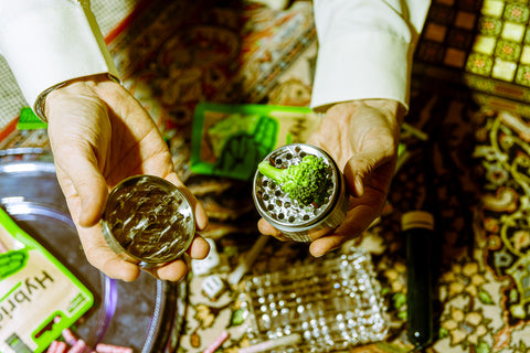 Grinder Edelstahl geöffnet in zwei Teilen, von einem Mann in der Hand gehalten, gefüllt mit Brokkoli – stilvolles und funktionales Zubehör zum Kräutergrinden
