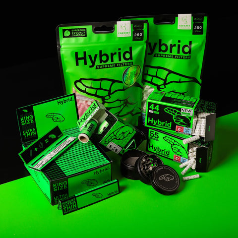 Hybrid Supreme Filters Medium Bundle mit 250er-Bags, Longpapers, Filterboxen, Rolls und schwarzen Grinders auf grün-schwarzem Setup.