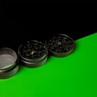 Keramik Grinder Hybrid geöffnet, Mahlring und Siebkammer schräg angeordnet auf Grün.