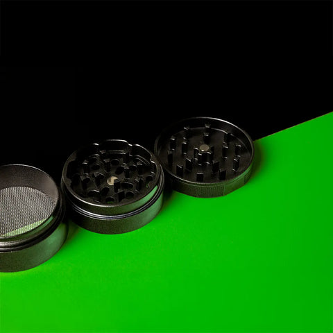 Keramik Grinder Hybrid geöffnet, Mahlring und Siebkammer schräg angeordnet auf Grün.