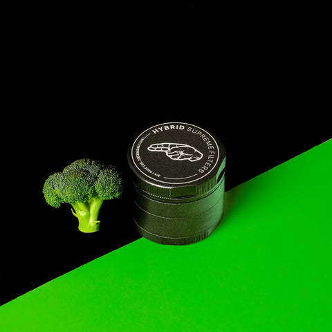 Geschlossener Keramik Grinder Hybrid neben einem Brokkoli als humorvoller Größenvergleich.