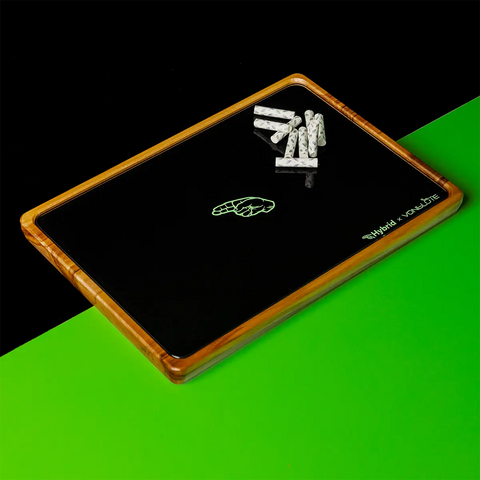 Hybrid x VonBlüte rolling tray aus Holz mit schwarzer Glasoberfläche und Aktivkohlefiltern – stilvolle Drehunterlage auf grün-schwarzem Hintergrund.