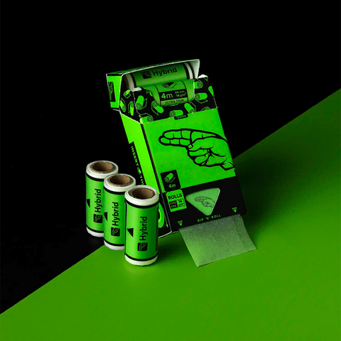 Geöffnete Hybrid Papers Packung mit herausgezogenem Papierstreifen aus der Rip 'n' Roll Öffnung, daneben drei einzelne King Size Slim Rollen mit 4 m ultradünnem Papier, 44 mm und 14 g/m²